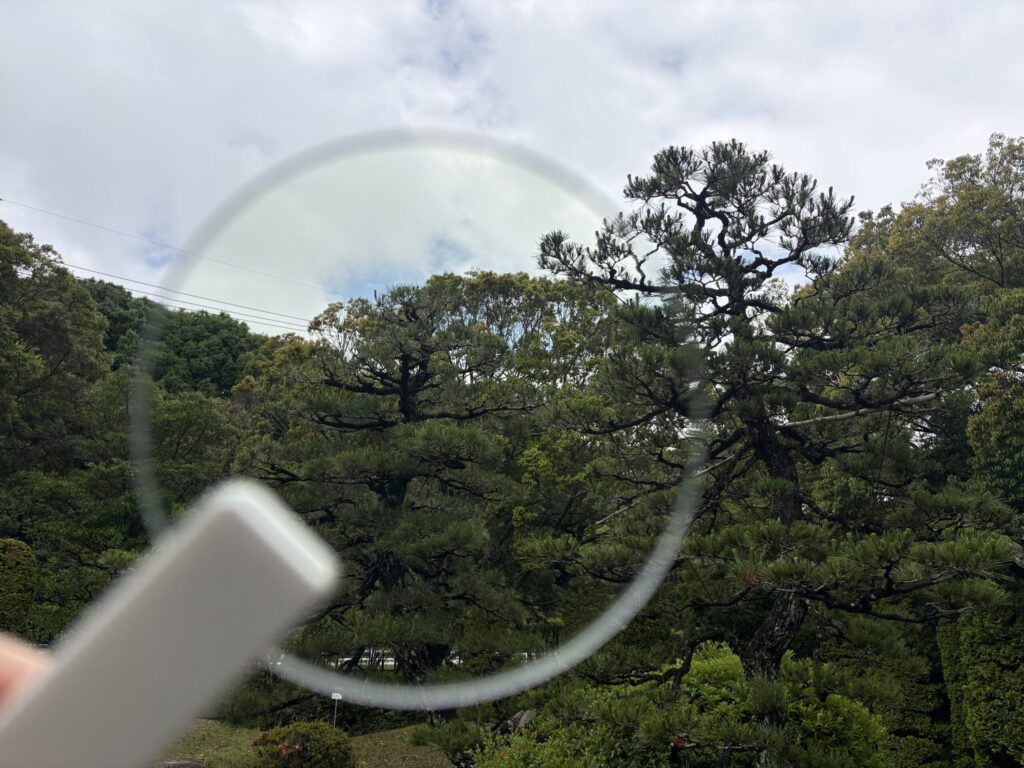 ルティーナを空にかざして、レンズ越しの色味を確認する画像